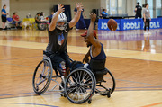 Two wheelchair football players make a move for control of the ball.