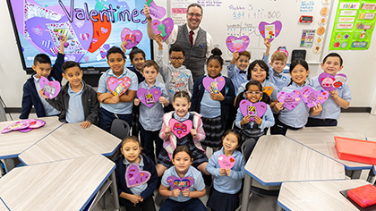 smiling group of 2nd grade children show off their handmade valentine's day cards