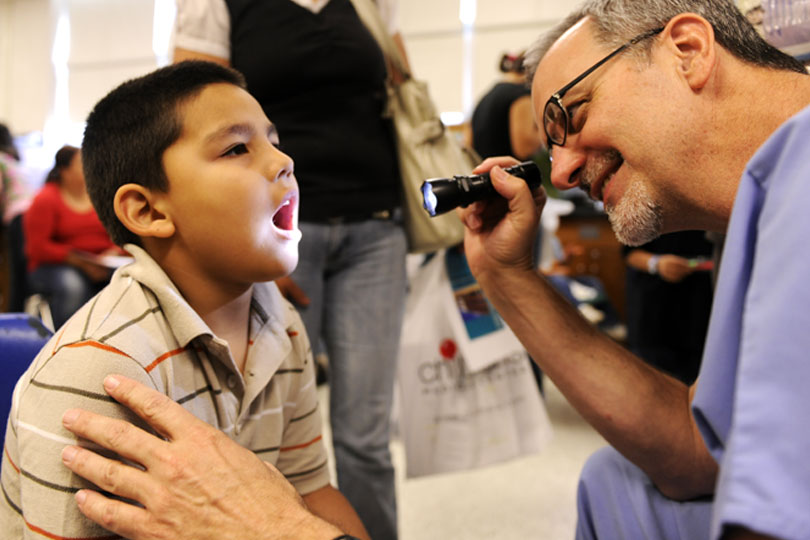A medical student looks a child's throat during a clinic at United to Serve