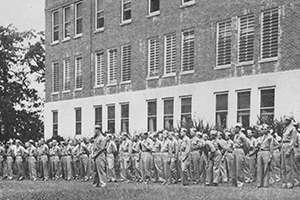 Soldiers lined in front of large brick building
