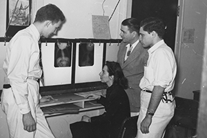 Three men, standing, and a woman seated, look up at an X-ray image