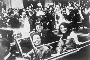 Jack and Jackie Kennedy, and John and Nellie Connally, riding in limousine with crowd in the background