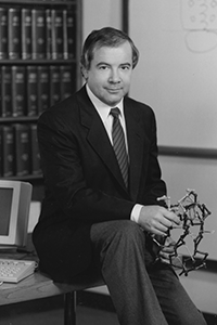 Johann Deisenhofer sitting on desk, holding molecular model