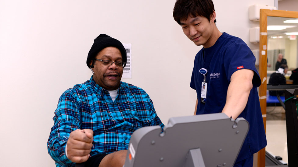 Student working with a patient on an exercise machine