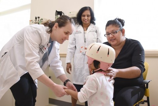 Laura Elguea (right) adjusts the helmet on her daughter Naomi, a 3-year-old Rett syndrome patient at UT Southwestern. 