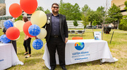 Jacob Hopgood staffs the LGBTQIA Alliance BRG table with smiles and celebratory balloons.