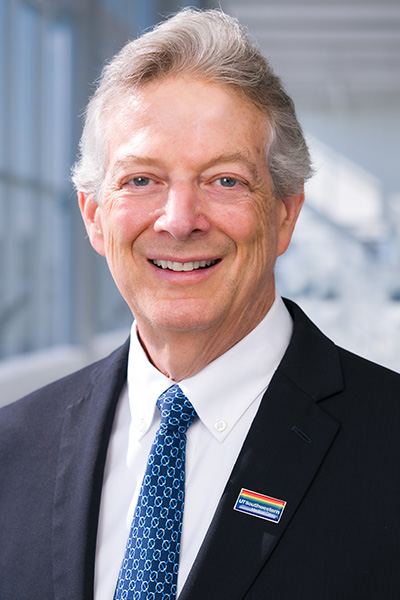 headshot of  Dr. Andrew Zinn grey haired man in grey blazer and blue tie