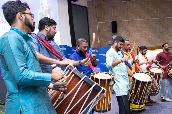 row of Asian men drumming on traditional instruments