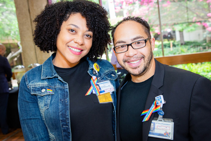 A woman with dark curly hair posing next to a man with dark hair, with glasses