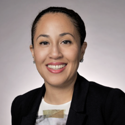 A woman with brown hair, wearing a white top and black blazer