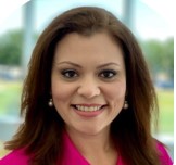 A woman with brown hair, wearing a red blazer