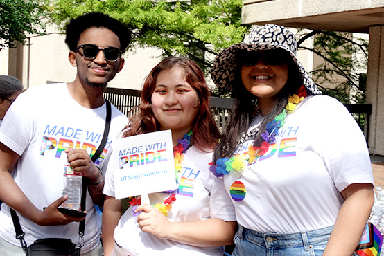 Three young people smiling and wearing shirts that read Made with Pride.