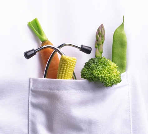 vegetables and stethascope showing over the top of a pocket on a white coat