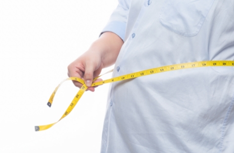 person wearing t-shirt holds measuring tape around waist