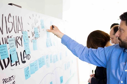 A man posts sticky notes on a board