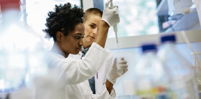 A woman holds a pipette to a test tube