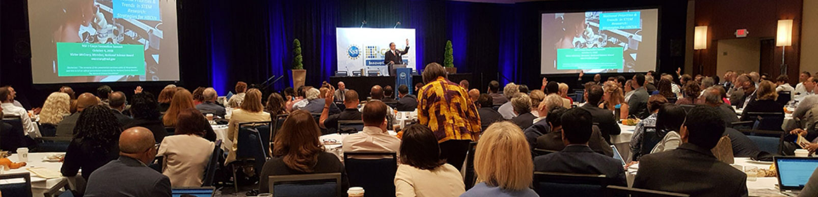 A man makes a presentation in front of a large room of people