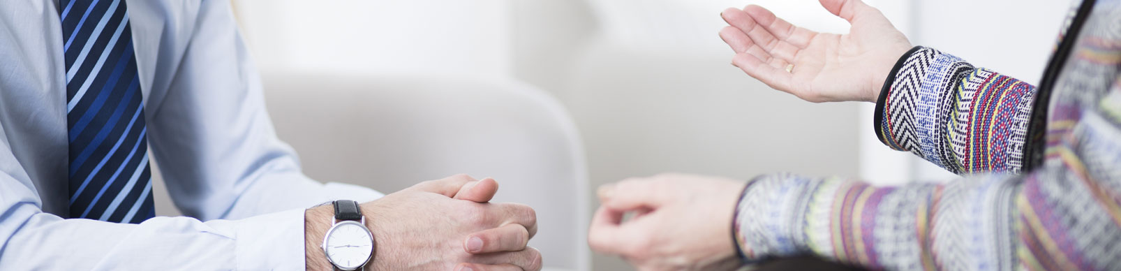 two people seated facing each other in discussion, showing just arms and hands in motion