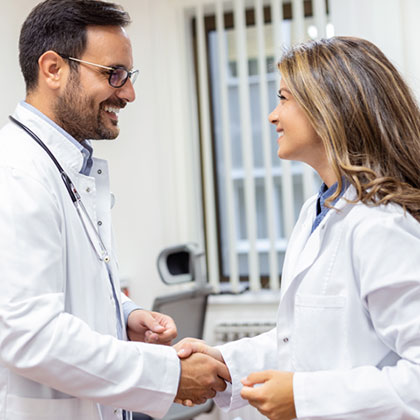 male and female doctors in white coats shake hands