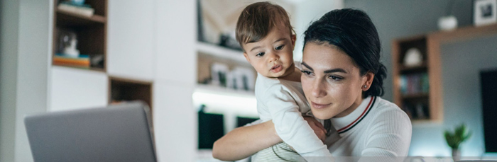 Woman holding child while working on computer