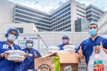 Health care workers hold containers of food that were donated to the hospital