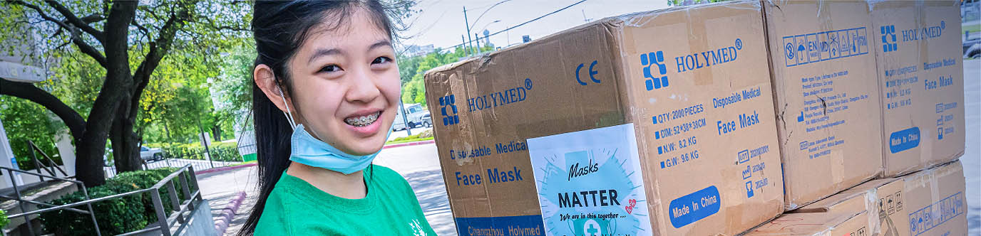 Valerie Xu standing beside a tall stack of boxes of masks