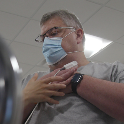 A man in shorts, a blue shirt, and a face mask works with ropes in physical therapy