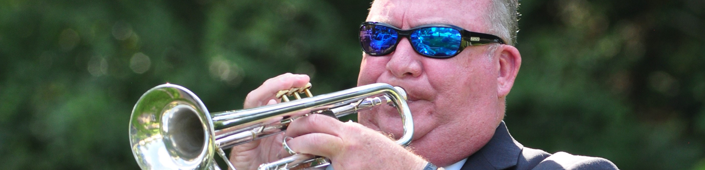 A man wears sunglasses and plays the trumpet