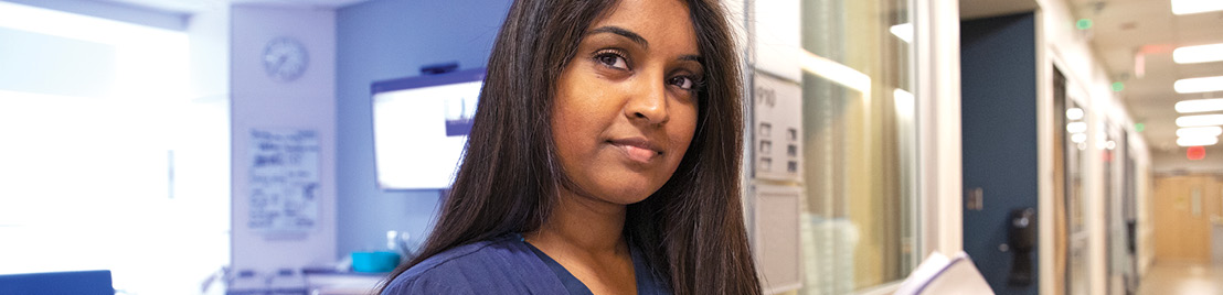 A woman with dark hair wearing blue scrubs