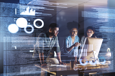 Two women and a man look at a computer monitor