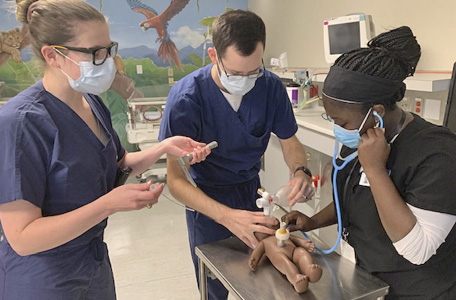 A male and two female medical students care for a newborn baby during simulation training