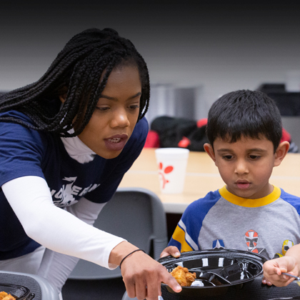 A young woman helps a small boy in a classroom