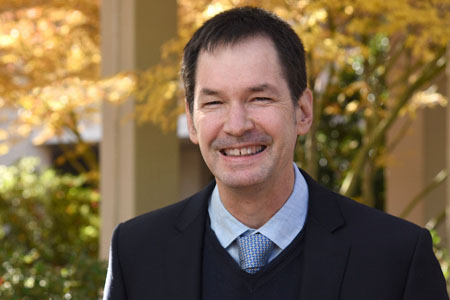 A man with dark hair, smiling for a photo