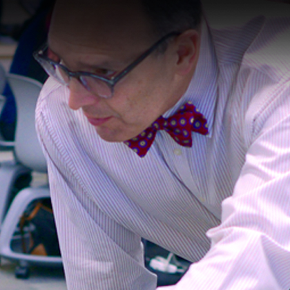 A man wearing a red bowtie with white polka dots and glasses, teaching in a classroom