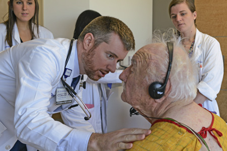 A medical professional checking an elderly man's heart