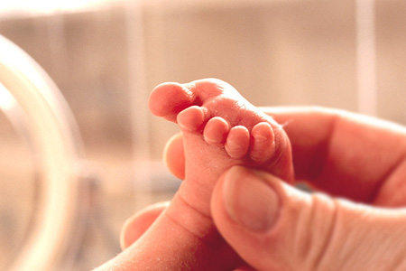 A grownup's hand holding a baby's foot
