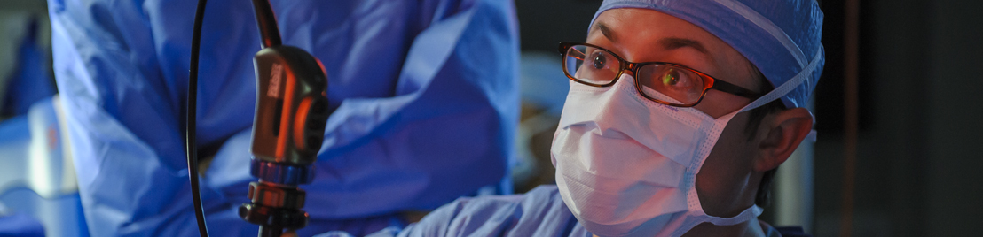 A medical doctor, wearing masks, looking down in operating room