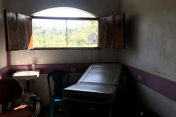 A clinic room with a sink, chair, and exam table