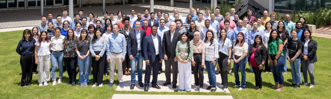 A group of men and women from different diverse backgrounds, taking a picture outside