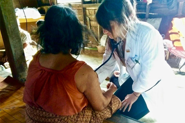 Taylore King listens to a patient's heart during a home visit in Surat Thani