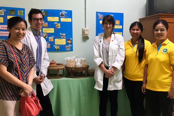 Taylore King and four colleagues at a hospital in Thailand with a table of packets of traditional herbal remedies