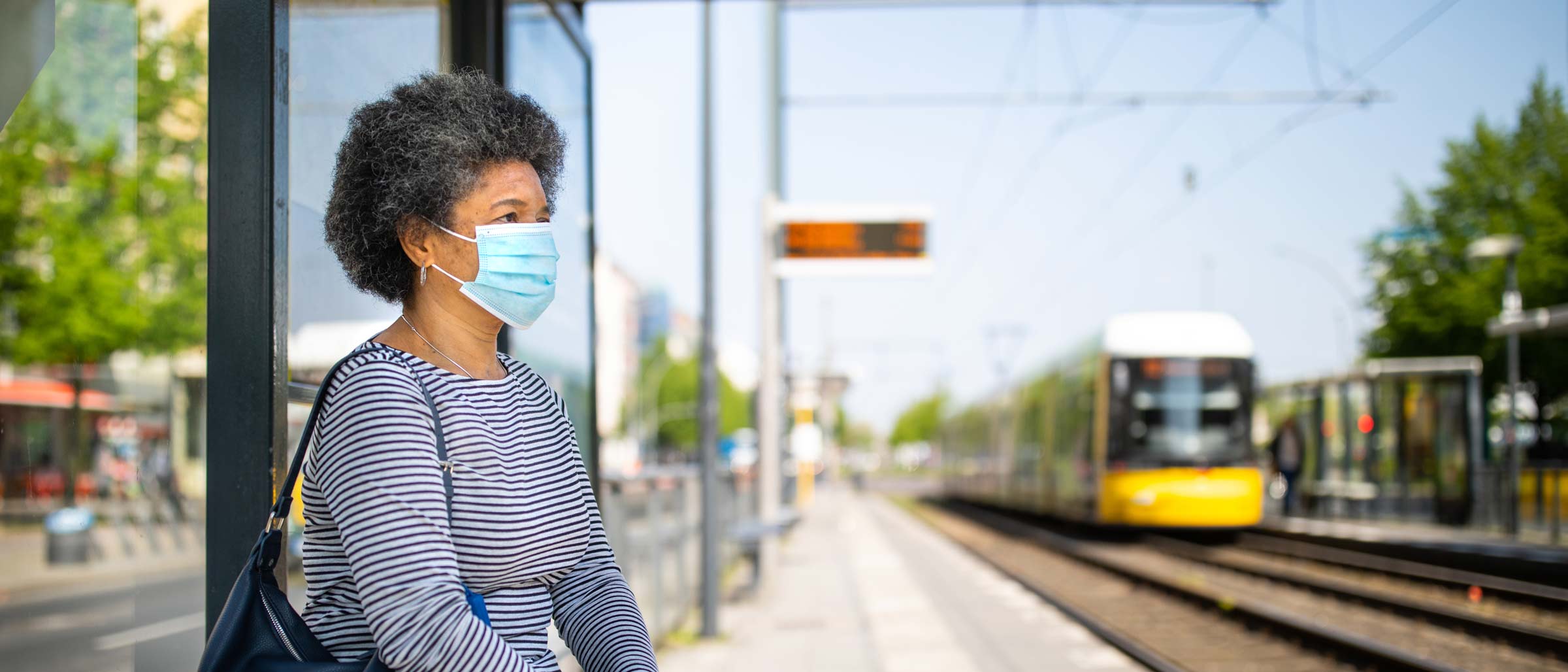 Woman wearing mask sitting at train station