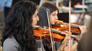 Dr. Ananthakrishnan and an orchestra member behind her demonstrate the perfection of their musical craft.