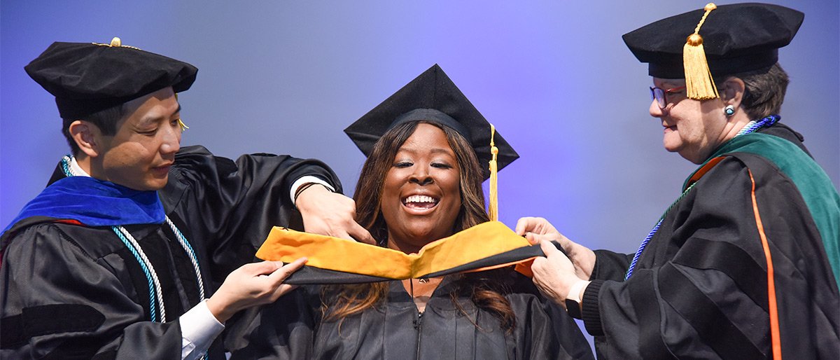 student being robed by two professors