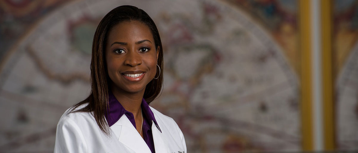 Woman in white lab coat in front of map