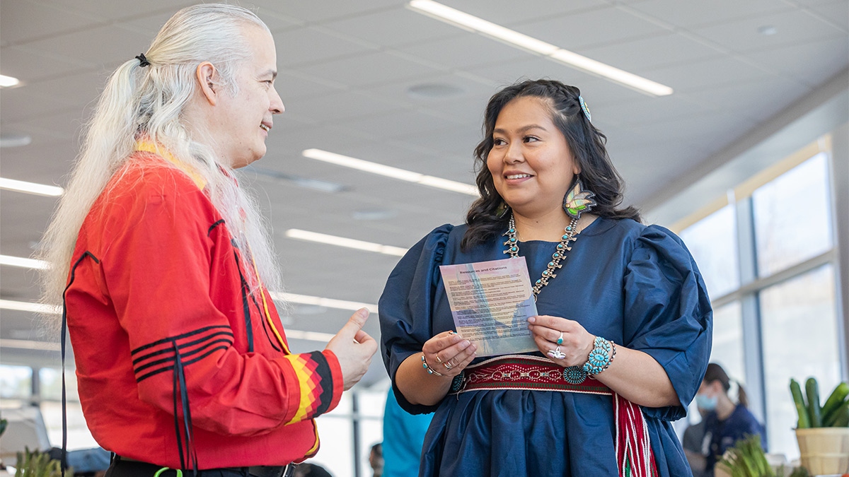 man with long blond hair in red shirt and woman in blue denim cultural dress