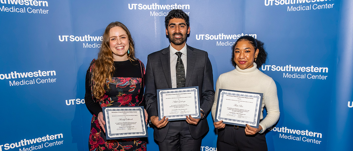 Three smiling people holding award certificates.