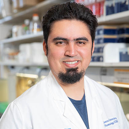 Man in white lab coat with dark hair, goatee