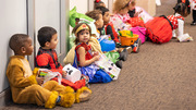 All lined up and sitting with their Halloween treats are children in adorable costumes.