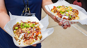 An employee shows off their brisket and macaroni and cheese-topped baked potatoes.